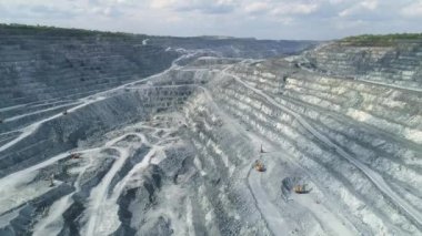 Dev asbest ocağının hava manzaralı dikey manzarası. Taş ocağının içinde kamyonlar için bir kazıcı ve serpentin yol var. Yaz güneşli bir gün. Taş ocağının tepesinde bir orman var.