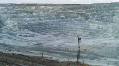 Dev asbest ocağının tepesindeki hava manzaralı demiryolu. Taş ocağının içinde kamyonlar için bir kazıcı ve serpentin yol var. Yaz güneşli bir gün. Taş ocağının tepesinde bir orman var.