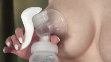 Genç anne bebeği için anne sütü pompası kullanıyor ve anne sütü pompalıyor. Tamamlayıcı beslenme için anne sütü, bebek besin.