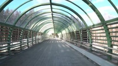Yeni inşa edilmiş modern yaya köprüsünün içinde yürümek, uzun demir ayak köprüsünün boş olması. Uzun bir koridorda. Köprünün altından arabalar geçiyor.