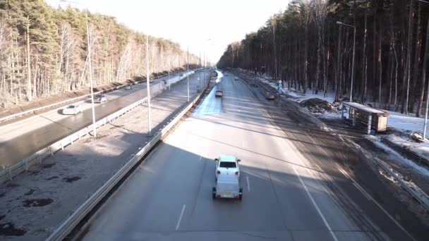 高速道路のビュー新しく建てられた近代的な歩行者用橋の中 車の高速道路では 空の長い鉄の足の橋を駆動します 長い廊下を通って道 雪が森の中にある — ストック動画