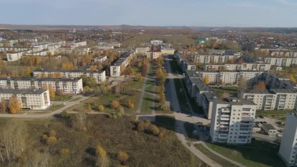 ソビエトパネル5階建てと9階建ての家 路地や文化の家と地方の秋の都市の空中ビュー 車は道路を走る 人々は黄金の路地に沿って歩く 木の上には黄色の葉がある — ストック動画