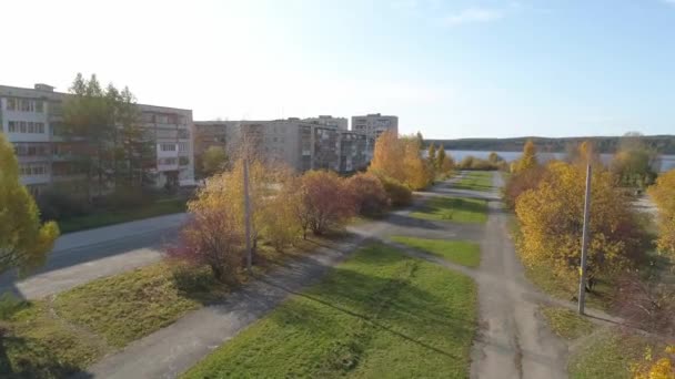 池の近くにソ連のパネル5階建てと9階建ての家と地方の秋の都市の木や草を持つ公園のドローンビュー 木の上には黄色の葉がある 葉は木から落ちる 晴れた日 — ストック動画