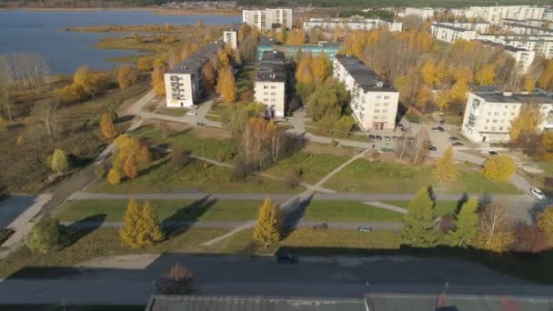 从空中俯瞰五层高的苏联式住宅 座落在秋城的小巷和池塘边 人们沿着金色的小巷走着 汽车在路上行驶 树上有黄色的叶子 阳光灿烂 — 图库视频影像