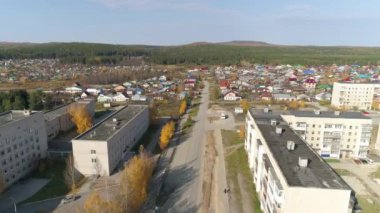 Rus taşrasında tek katlı evleri olan yerleşim alanının havadan görünüşü. Sol tarafta ise hastane var. İki, üç ve beş katlı eski Sovyet evleri. Ufukta dağlar ve orman görünüyor. Sonbahar güneşli bir gün.