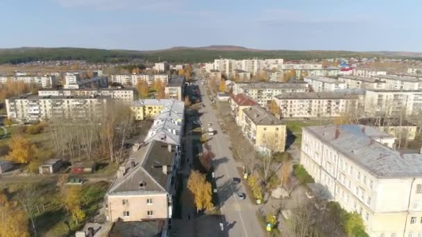 低建物と地方ロシアの都市の空中ビュー 9階建ての古いソ連の家 車が通りを走っている 地平線には山や森が見える 秋の晴れた日 — ストック動画