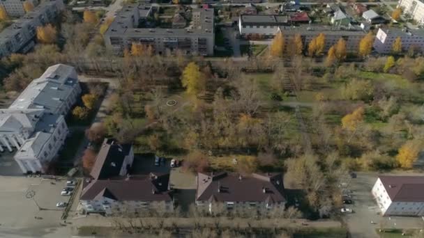 ロシアの地方都市の文化の家の隣にある公園の空中ビューでは バルコニー付きの3階建ての古いソ連の家 車が通りを走っている 市内には黄色の葉を持つ木がたくさんあります 秋の晴れた日 — ストック動画