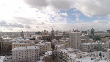 Büyük kış şehrinin havadan görünüşü. Modern yüksek binalarda ve eski binalarda. Çekimin merkezinde, şehir yönetim binası var. Bulutlu bir gün. Bulutlar gökyüzünde hızla uçar