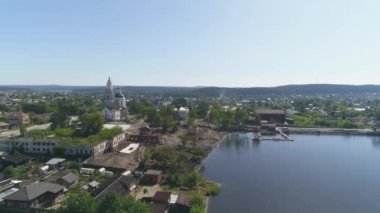 Şehir merkezindeki bir baraj inşaatının havadan görüntüsü. Eski kilisenin ve eski evlerin yeniden inşası. Göletin yanında eski bir fabrika var. Ağaçlar ve inşaat malzemeleri kıyıda. Yaz güneşli bir gün