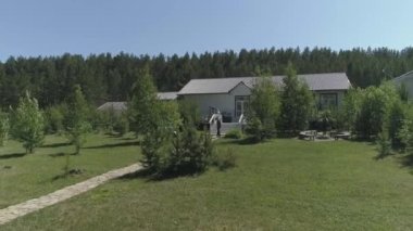 Kutlamalar ve düğünler için olan ziyafet evinin arka bahçesi. Avluda bir çim, bir patika, ağaçlar arasında bir salıncak ve bir bisiklet. Konuklar tatil beklentisiyle yürüyorlar..