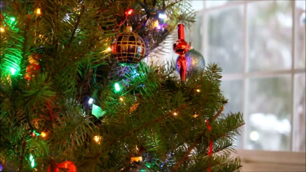 Árbol de Navidad y decoraciones frente a una ventana nevada . — Vídeo de stock