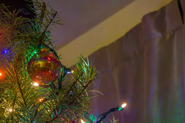 Σαφές κόκκινο χριστουγεννιάτικο στολίδι που κρέμεται από ένα χριστουγεννιάτικο δέντρο — Φωτογραφία Αρχείου