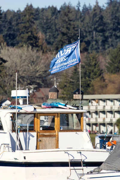 a tattered Trump 2020 flag atop a luxery boat