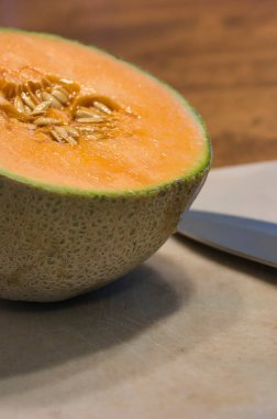 Kavun ve bıçak masanın üzerinde beyaz kesme tahtasında.