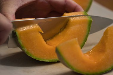 Keskin bir bıçak olgun bir kavunu kesiyor.