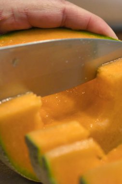 Keskin bir bıçak olgun bir kavunu kesiyor.