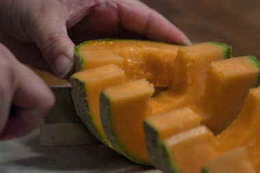 Tezgahta taze kavun doğrayan bir kadın.