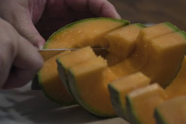 Tezgahta taze kavun doğrayan bir kadın.