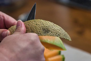 Tezgahta taze kavun doğrayan bir kadın.