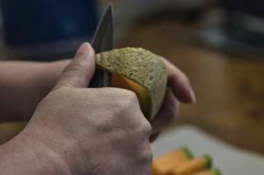 Tezgahta taze kavun doğrayan bir kadın.