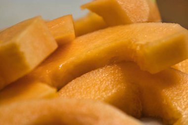 Tezgahta taze kavun doğrayan bir kadın.