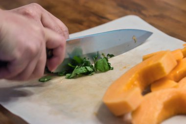 Kadınların elleri fesleğen yapraklarını dilimlenmiş kavunun yanında ince ince doğruyor.