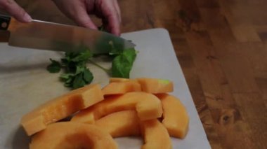 Fesleğen ve maydanoz dilimlenmiş kavunun yanında doğranır.