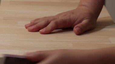 Kadınların elleri ahşap tezgahın üzerinde bir zımpara bloğunu itiyor.