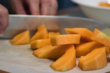 Keskin bir bıçak, kavun parçalarını kesiyor.