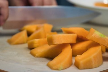 Keskin bir bıçak, kavun parçalarını kesiyor.