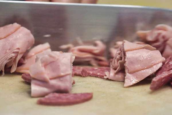 A knife chopping up lunch meat for deli salad — Stock Photo, Image