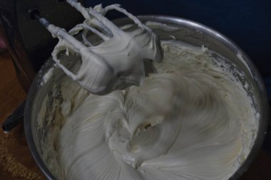 Çırpılmış krema kaplı bir elektrikli mikser.