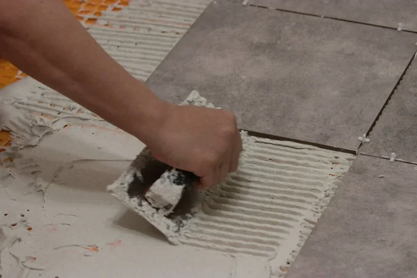 Womans hand laying down thinset to tile a floor — Stock Photo, Image