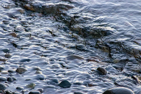 Small waves flowing in over rocky shoreline — Stock Photo, Image