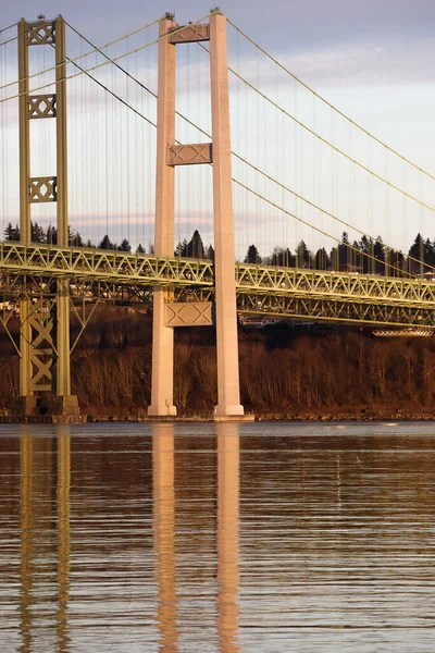 Stöd för bron reflekteras av vatten vid solnedgången — Stockfoto