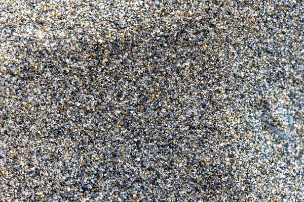 Brillanti macchie colorate di pietra che compongono la sabbia lungo la riva — Foto Stock