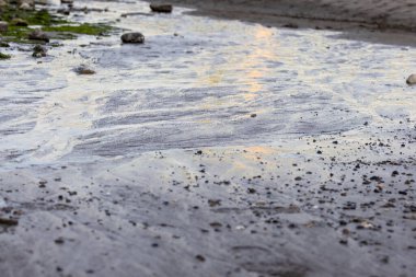 Gün batımında karadan akan su yanardöner renkleri gösterir.