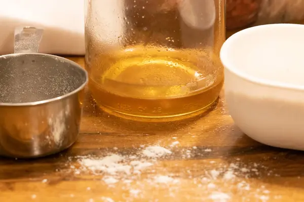 Tazas de medición y aceite sentado sobre una mesa —  Fotos de Stock