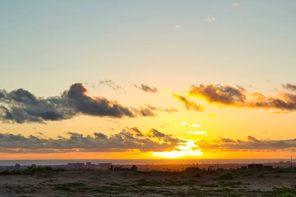Dourado pôr do sol brilhante através de nuvens sobre a praia — Fotografia de Stock