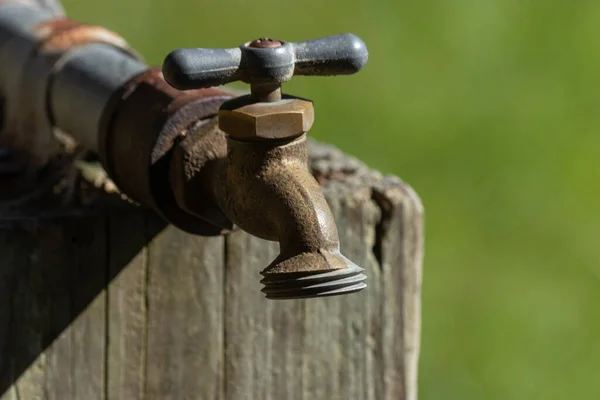 Vieux robinet d'eau métallique boulonné sur un poteau en bois — Photo