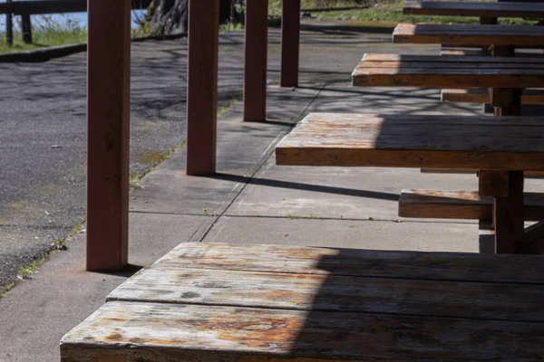 Empty picknick tables lined up under a pavilion — Stock Photo, Image