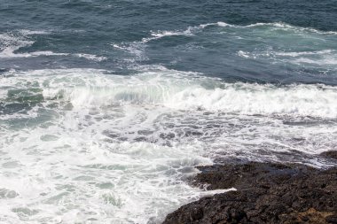 Köpüklü beyaz dalgalar Karanlık Kıyı Kayalıkları 'na çarpıyor. Yüksek kalite fotoğraf