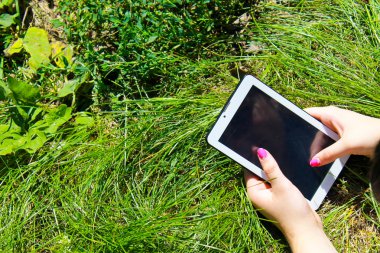 Çim döşeme bir tablet holding kadının eller
