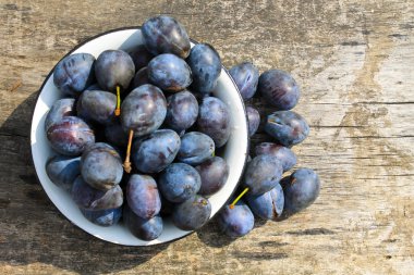 Eski ahşap arka plan üzerinde rustik kase taze Erik