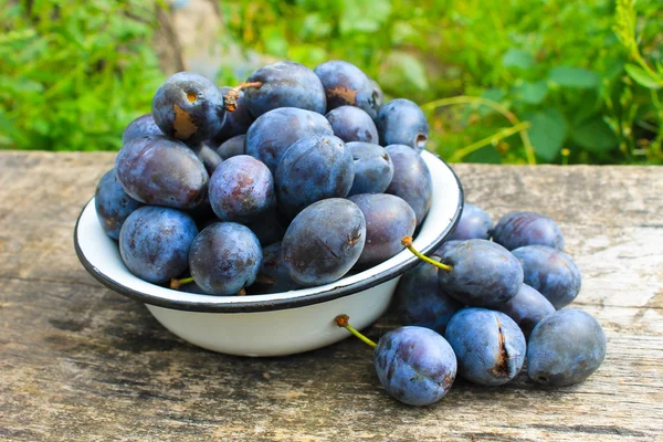 Frische Pflaumen in rustikaler Schale auf altem Holzgrund — Stockfoto