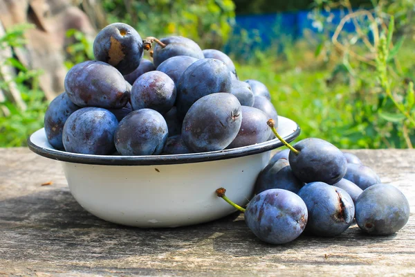 Prugne fresche in ciotola rustica su fondo legno antico — Foto Stock