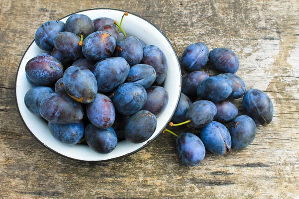 Prugne fresche in ciotola rustica su fondo legno antico — Foto Stock