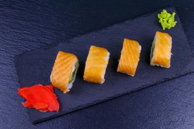 Suşi Philadelphia 'yı siyah bir levhada yuvarlıyor. Üst görünüm