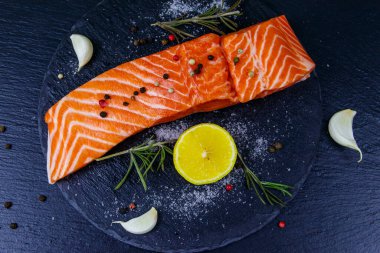 Çiğ somon fileto ve siyah tahta üzerinde baharat. Üst görünüm