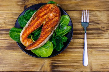 Ahşap masada ıspanaklı ızgara somon bifteği. Üst görünüm